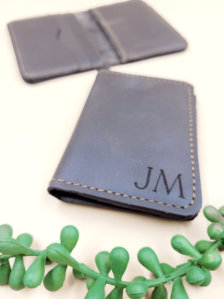 Men's leather bi-fold wallet with personalised monogram, displayed next to an open wallet showing multiple card slots for organised storage.