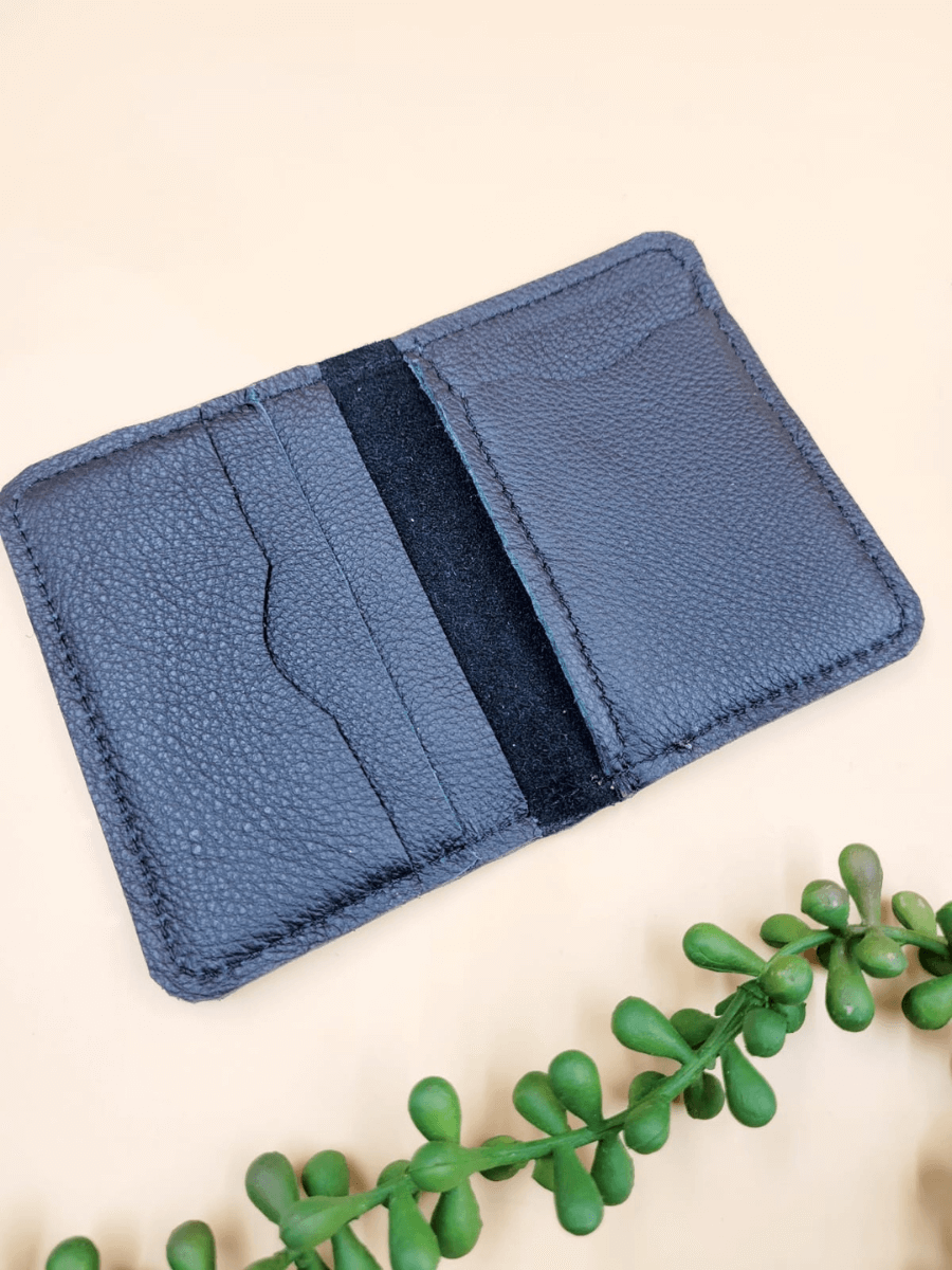 Personalised men's leather bi-fold wallet with card slots, shown open on a light background, next to green plant accents.
