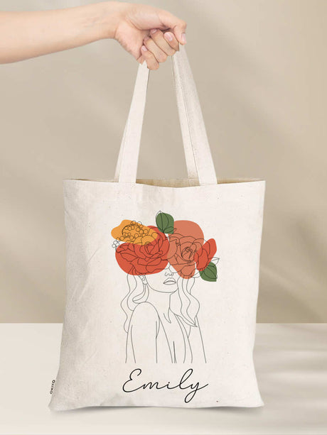 Hand holding a personalised cotton tote bag with floral design and 'Emily' text, highlighting eco-friendly and stylish gift options.