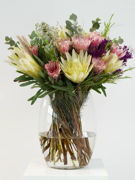 Vase with a striking arrangement of proteas, pincushions, eucalyptus, and fynbos, celebrating South African women's strength and beauty.