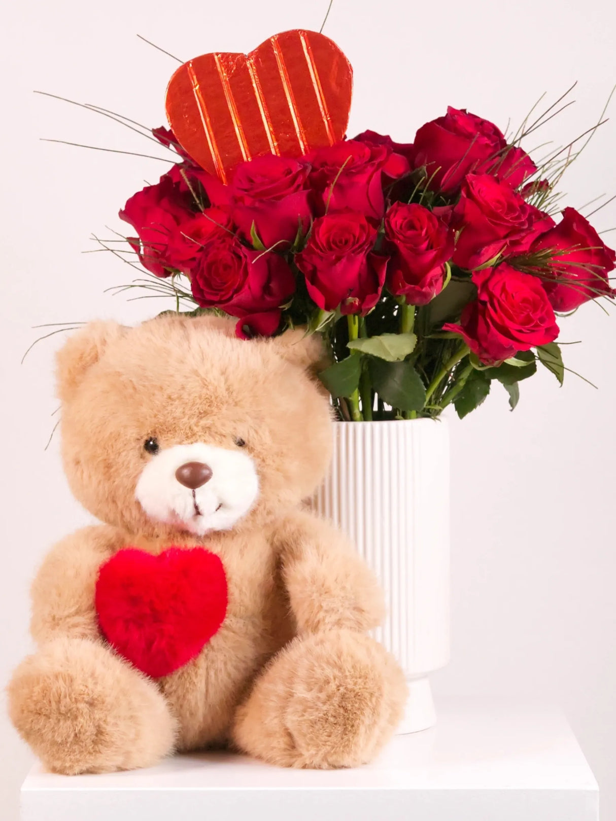 Teddy bear with a red heart and bouquet of red roses on a white background