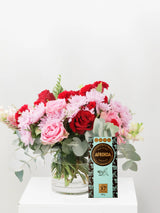 Bouquet of red and pink flowers with a box of Afrigold coffee on a white background