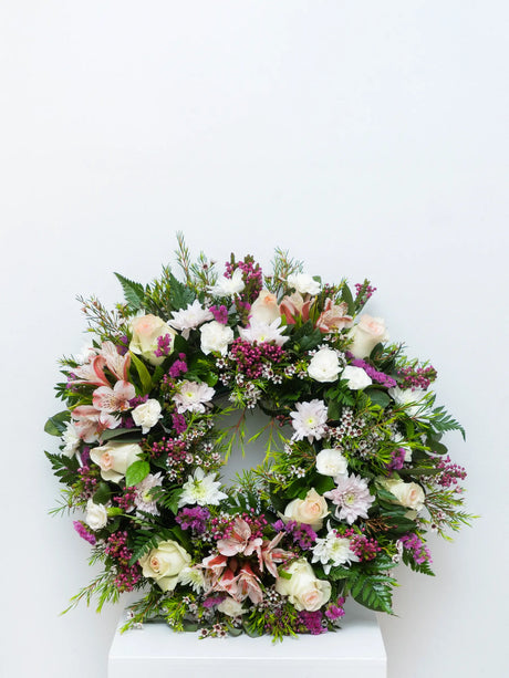 Soft pink and white round wreath for memorials and funerals.