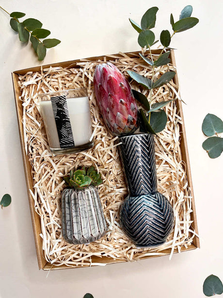 Gift box with Geskenk Charcoal Vase, Bud Vase, Protea bloom, penny gum, and Donation Candle for a serene, elegant ambiance.