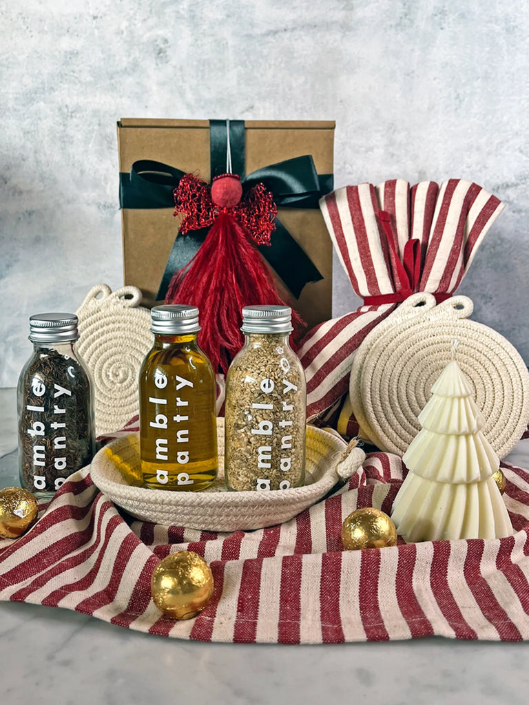 Decorative gift set with bottles, a box, and Christmas-themed items on a striped cloth.