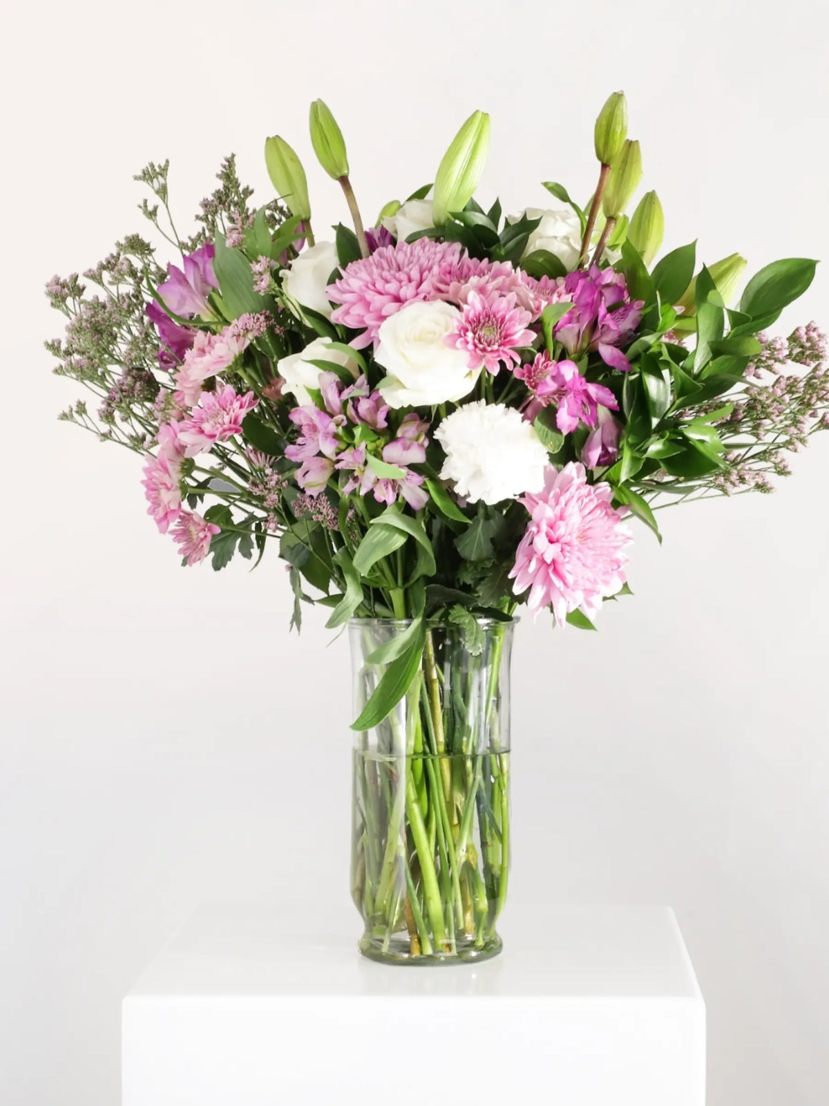 Pink and white luxury flower bouquet with pink chrysanthemums, white roses, pink alstroemeria, white carnations and eucalyptus in clear glass vase - elegant mixed arrangement