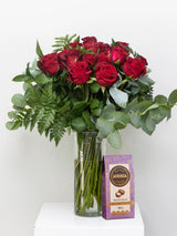 Bouquet of red roses in a vase with a box of Afrida chocolate on a white background
