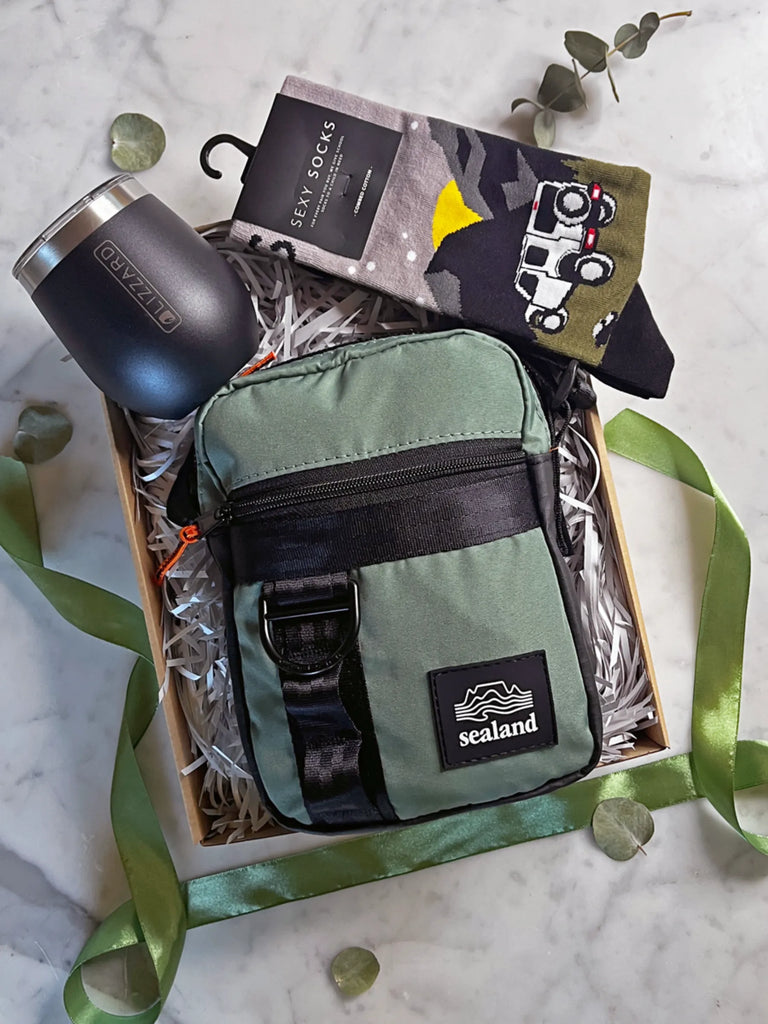 Green bag with 'sealand' logo, black tumbler, and socks in a box on a marble surface.