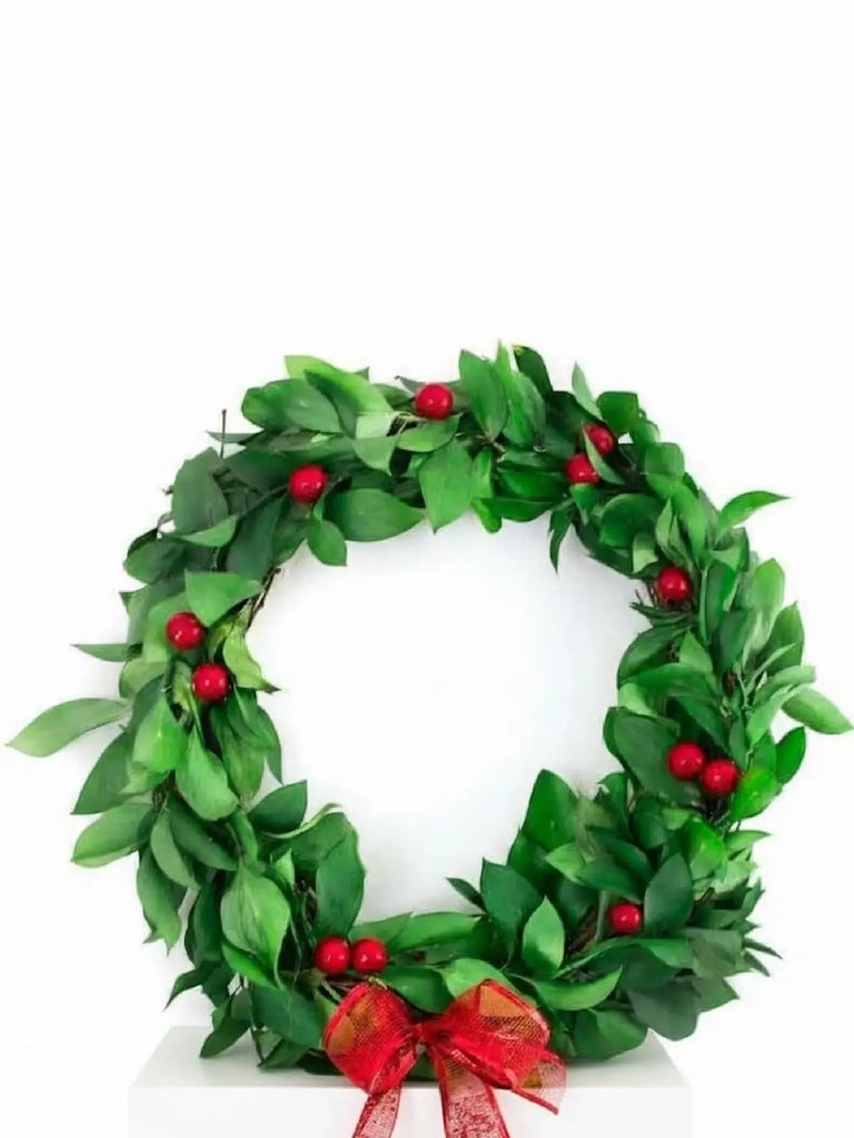 Traditional green Christmas wreath with red berries and red bow - classic festive door decoration