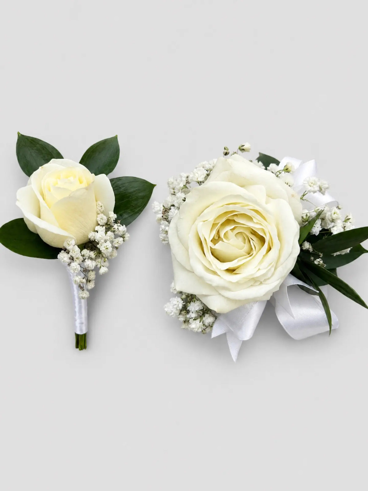 White rose boutonniere and corsage on a light gray background