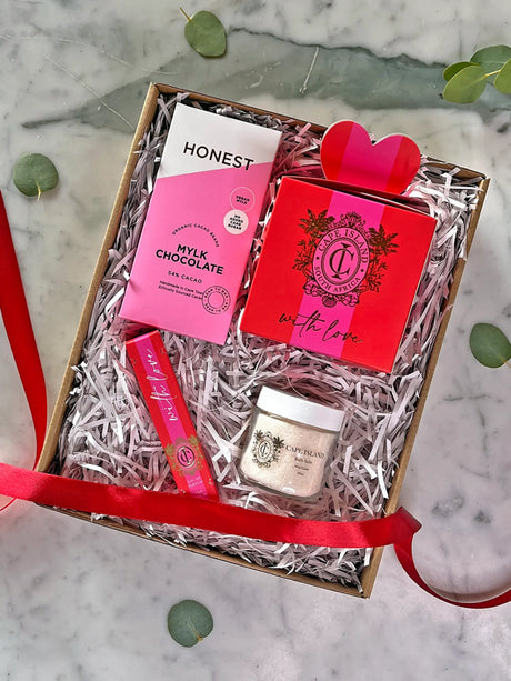 Gift box with chocolate, lip balm, and cream on a marble surface