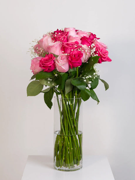 Light pink and hot pink rose bouquet with baby's breath in glass vase
