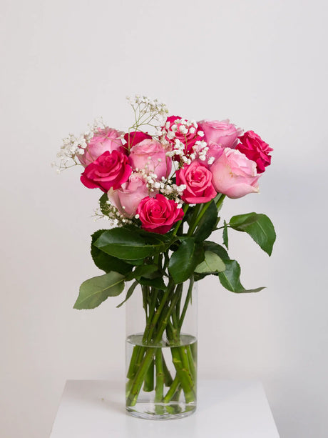Light pink and hot pink rose bouquet with baby's breath in glass vase