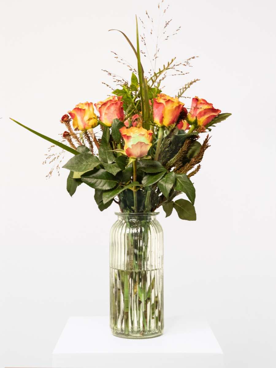 Orange Rose Bouquet with lush greenery in glass vase, crafted by local South African florists, showcasing seasonal flower arrangement.