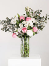 Fresh pink and white flower arrangement with pink roses, white alstroemeria, white carnations and eucalyptus in clear glass vase - classic romantic bouquet