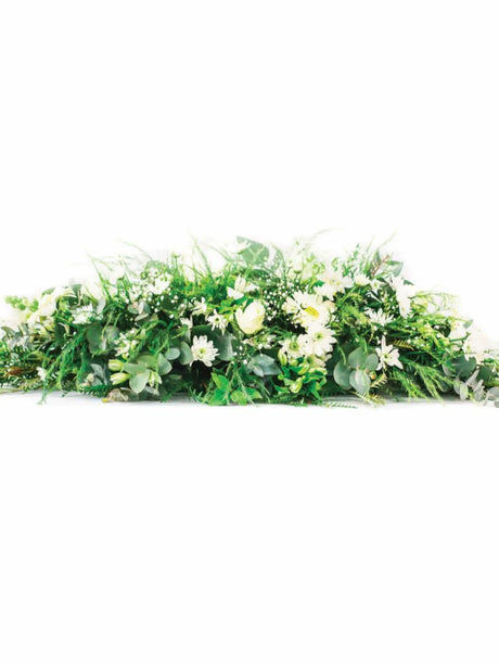 Coffin or Casket Spray of mixed seasonal flowers and greenery for memorial and funeral services.