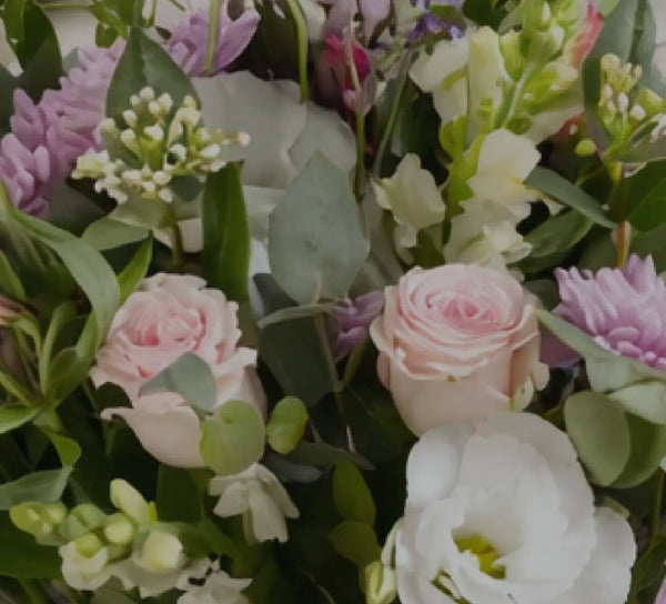 Bouquet of flowers with pink, white, and purple roses, and green leaves.