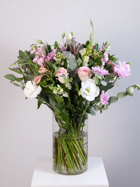 Pastel mixed bouquet with pink roses, white lisianthus, light pink chrysanthemums and eucalyptus in glass vase