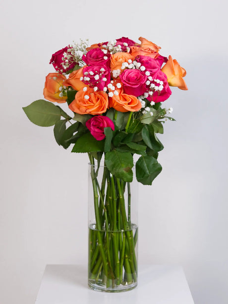 Hot pink and orange rose bouquet with gypsophila in glass vase
