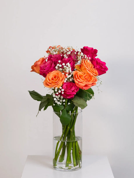 Hot pink and orange rose bouquet with gypsophila in glass vase