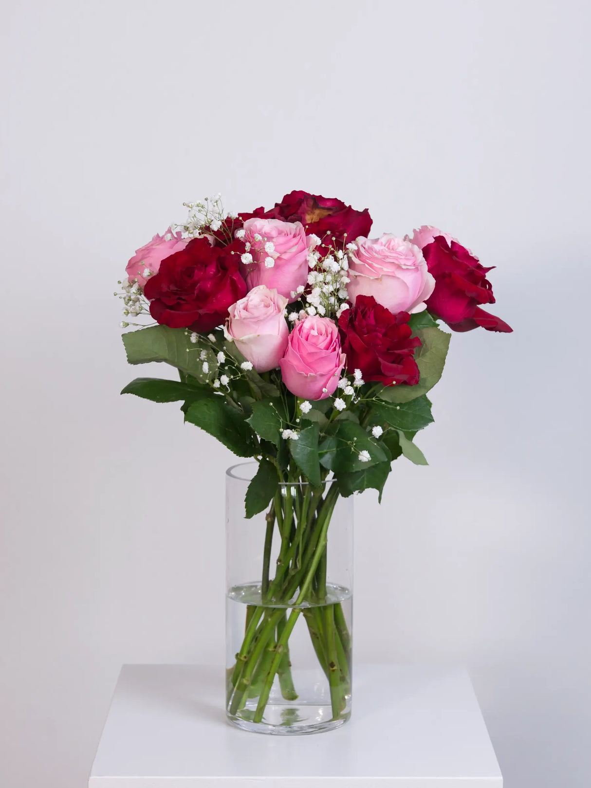 Pink and red rose bouquet with gypsophila in a glass vase