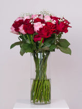 Bouquet of red and pink roses in a clear vase on a white background