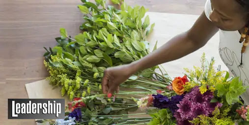 Person arranging flowers on a table with 'Leadership' text overlay