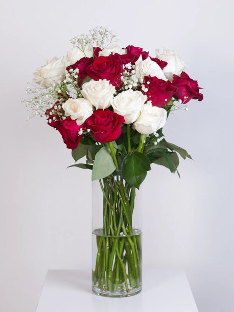 Red and white rose bouquet with baby's breath in a glass vase
