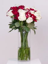 Red and white rose bouquet with baby's breath in a glass vase