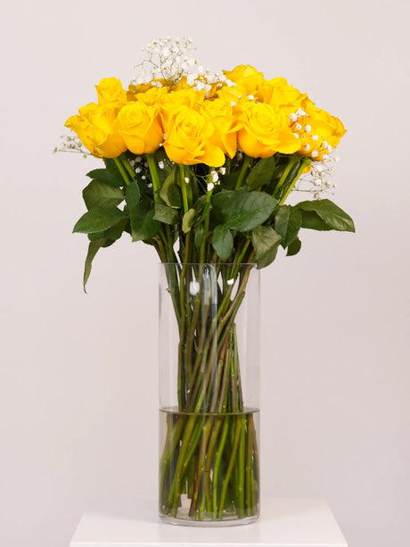 Bouquet of yellow roses in a clear vase on a white background