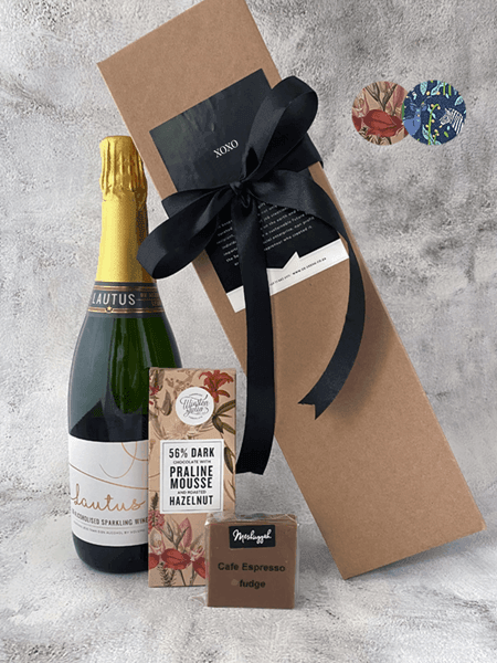 Elegant gift set with Lautus sparkling wine, artisanal chocolate bar, and fudge, packed in a kraft box tied with a black ribbon.