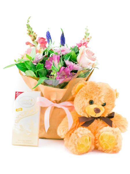 Celebrate a baby girl with a Lindt box, floral bouquet, and teddy bear. Local florist arrangement may vary. Ideal gift set.