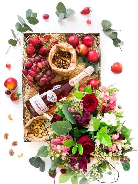 Vegetarian gift box with nuts, nectarines, strawberries, and non-alcoholic champagne, accompanied by a floral arrangement.