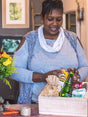 Local florist curating a Florist's Choice Gift Box filled with snacks and goodies, supporting South African local businesses.