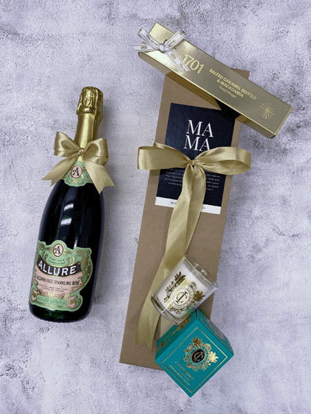 Golden Celebration gift set with non-alcoholic Pinot Noir Chardonnay, salted caramel brittle, macadamia nougat, and beach candle.