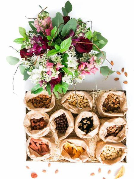 Luxury jumbo snack box with dried fruits, nuts, and vibrant floral arrangement in red, white, and pink, perfect gift idea.
