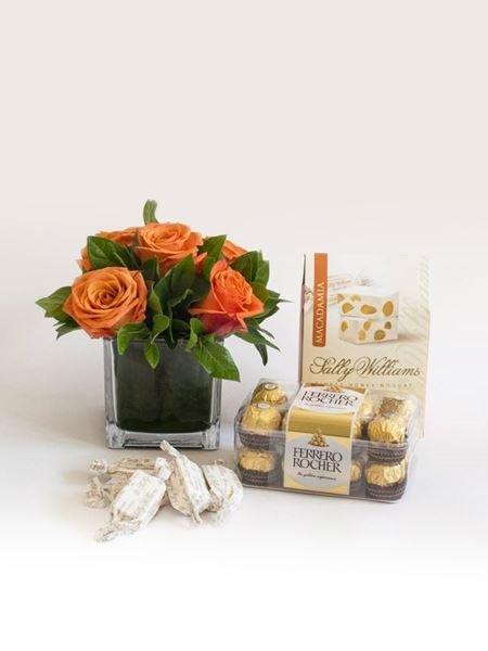 Orange rose arrangement with assorted sweets, featuring Ferrero Rocher chocolates, perfect gift for sweet and flower lovers.