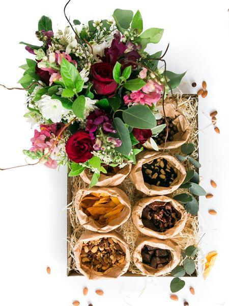 Savoury jumbo snack box with biltong, dried meats, nuts, dried fruits, and a floral arrangement in a clear glass vase.