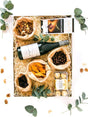 Gift box with non-alcoholic red wine, Lindt chocolate, Ferrero Rocher, nuts, Maltesers, and dried fruit, beautifully presented with greenery.