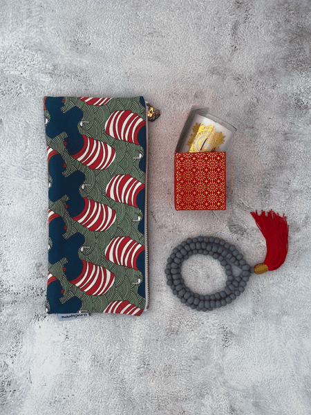 Supreme Joy gift box with African Lady pencil case, Cape Island celebratory candle, and prayer beads on a textured surface.