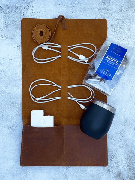 Genuine leather cable holder with cords, black Lizzard cup, and biscotti set on a textured surface for organized style on the go.