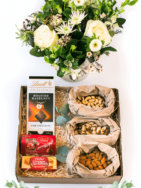 Luxurious gift box featuring fresh flowers, Lindt chocolate, Lindor Cream Caramels, cashews, almonds, and mixed nuts.