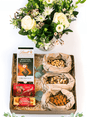 Luxurious gift box featuring fresh flowers, Lindt chocolate, Lindor Cream Caramels, cashews, almonds, and mixed nuts.